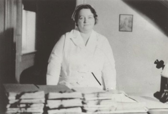 NURSE RENE M. CAISSE STANDING BEHIND HER DESK IN HER BRACEBRIDGE, ONTARIO CANCER CLINIC OFFICE WITH STACKS OF PETITIONS TO MAKE ESSIAC A LEGAL REMEDY