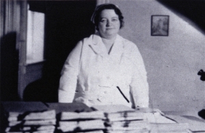 RENE CAISSE IN NURSE’S UNIFORM STANDING  BEHIND DESK WITH STACKS OF PETITIONS  FOR THE ONTARIO LEGISLATURE TO MAKE ESSIAC A LEGAL CANCER TREATMENT