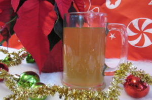 ESSIAC TEA IN A MUG SITTING ON A TABLE WITH WINTER HOLIDAY DECORATIONS